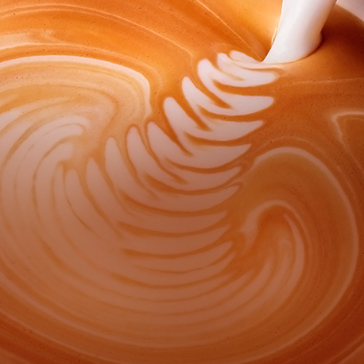 Chorro de leche cayendo en una taza de café latte.
