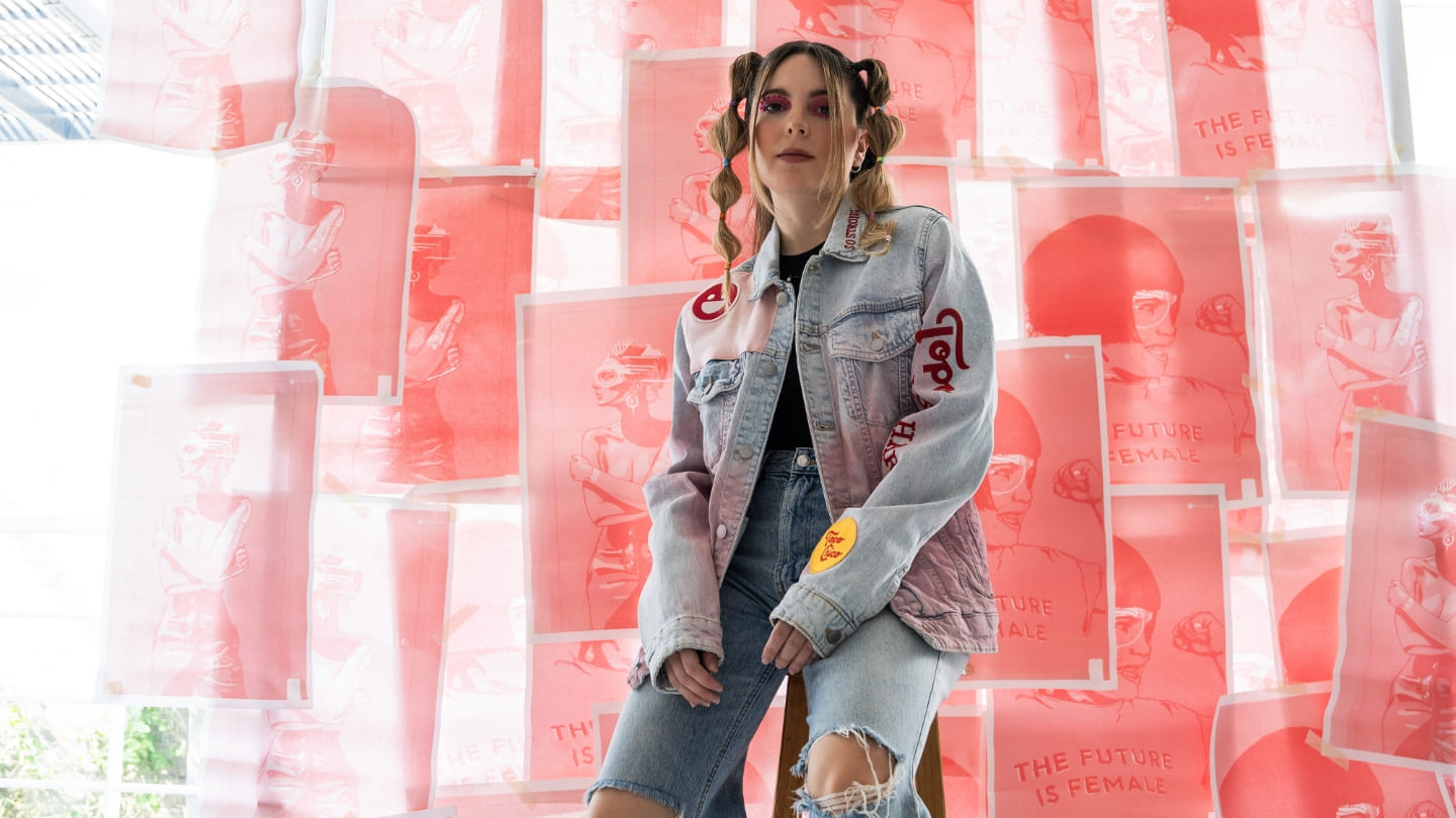 Imagen de una mujer con una Jean Jacket, en el fondo hay dibujos sobre papeles rosa